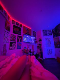 a bedroom with purple lights and pictures on the wall above it, along with a television