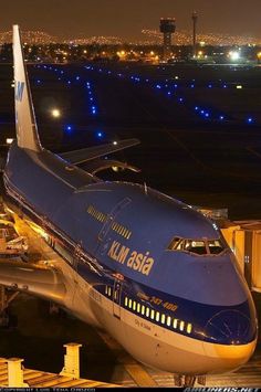 an airplane that is sitting on the tarmac at night with lights in the background