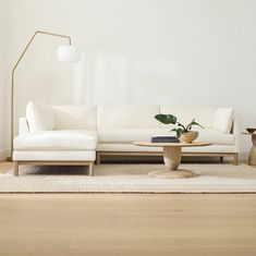 a living room with a white couch, table and lamp on the wall next to it