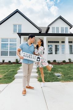 a man and woman standing in front of a white house holding a sign that says, we are the most beautiful address