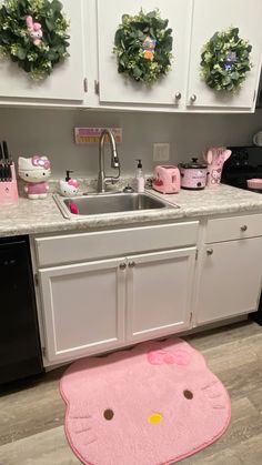 a kitchen with hello kitty rugs on the floor and white cabinets in front of it