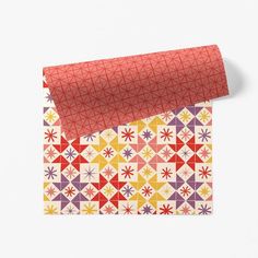 an orange wrapping paper with colorful geometric designs on the outside and inside, rolled up in half