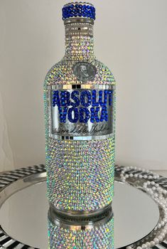 a bottle that is sitting on a table with some beads around it and the words absolut vodka in blue letters