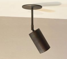 a ceiling light with a black shade hanging from it's center point and a white wall in the background