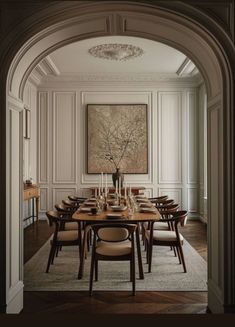 a dining room table with chairs and a painting on the wall behind it in an archway