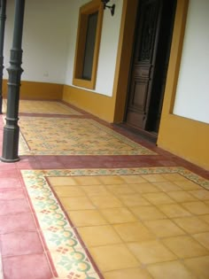 an empty hallway with yellow and red tiles on the floor next to a black pole