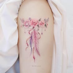 a woman's arm with a tattoo that has flowers on it and a feather