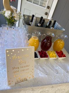 a table topped with lots of different types of fruit and drinks next to a sign