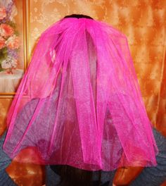 the back of a woman's head wearing a pink veil