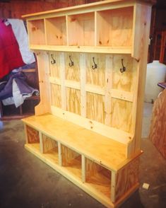 a wooden bench sitting inside of a room next to a wall with hooks on it