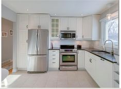 a kitchen with white cabinets and stainless steel appliances, including an oven, refrigerator, microwave, dishwasher and sink