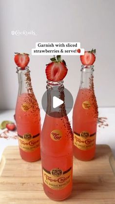 three bottles with strawberries in them sitting on a cutting board