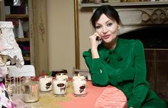 a woman sitting at a table with two candles in front of her and another candle behind her