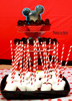 mickey mouse cupcakes on a plate with red and white striped paper straws