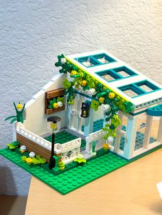 a lego model of a house with plants growing out of the roof and windows on top of it