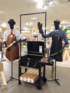 two mannequins dressed in aprons and hats stand next to an outdoor grill