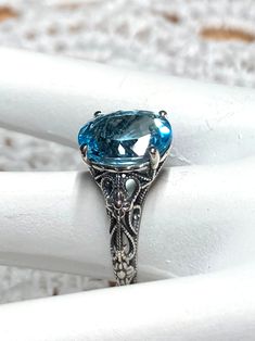 Natural Blue Topaz Sterling Silver RingMedieval Floral Design#D173 Introducing the D173 Medieval Floral ring! A gorgeous antique reproduction crafted to resemble its classic predecessors, while still boasting a modern touch. This enchanting piece of jewelry features an oval faceted gemstone, which has been prong set over stunning filigree, complete with intertwined floral designs and vine imagery that dance down the sides of the band. Thanks to this subtle balance of influences from both Art Deco and medieval styles, this stunning piece of jewelry is perfect for people who value a timeless look combined with modern creativity. The D173 Medieval Floral is sure to add a special touch to any outfit for a variety of occasions, making it an optimal choice for those seeking something special in Oval Blue Topaz Filigree Ring For Formal Occasions, Formal Oval Filigree Ring With Blue Topaz, Formal Oval Blue Topaz Filigree Ring, Handmade Oval Topaz Ring For Formal Occasions, Oval Topaz Ring Handmade For Formal Occasions, Victorian Oval Topaz Jewelry, Heirloom Oval Topaz Ring, Victorian Oval Topaz Ring Gift, Classic Oval Blue Topaz Filigree Ring