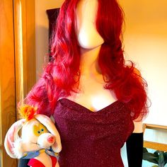 a red wig is holding a stuffed animal in front of a mannequin's head