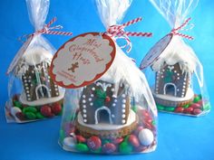 three bags filled with candy and candies on top of a blue surface, each bag has a gingerbread house in it