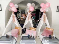 some pink and white balloons are in the shape of teepees