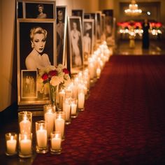 candles are lined up on the floor in front of pictures and flowers with marilyn monroe