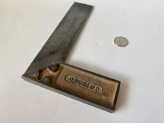 a knife that is sitting on top of a table next to a coin and another piece of metal