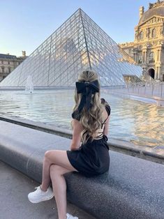 a woman sitting on a ledge looking at the pyramid