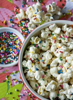 a bowl filled with sprinkles and popcorn on top of a wooden table