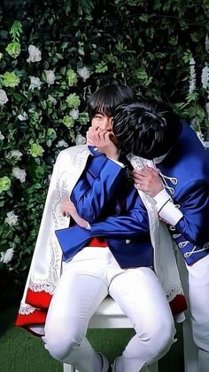 two people in white pants and blue jackets are sitting on a bench with their arms around each other