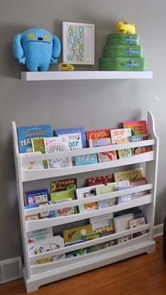 a white book shelf with books on it and a stuffed animal next to the shelves