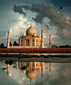 the tajwa mosque in india is surrounded by clouds and reflecting on the water