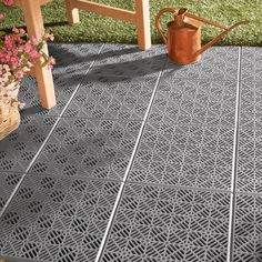 a metal grate sitting on top of a patio next to a wooden table and flowers