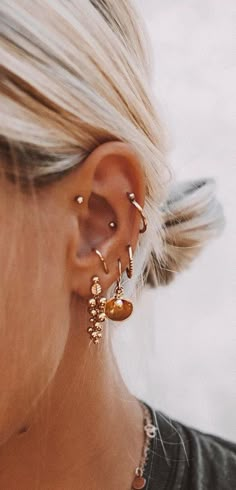 a close up of a person wearing ear rings and earrings with an orange circle in the background