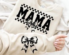 a woman's hands holding an unisex sweatshirt with the word mam printed on it