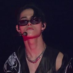 a woman wearing sunglasses and a leather jacket with a red light on her face in the dark