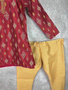 Boys Kurta Pajama Set in Raw Silk material with Cotton Lining. Kurta has Ikkat designs on the back, front and sleeves. The neckline has beautiful lace work and fancy buttons. Item : Boys Kurta PajamaReady to Wear : YesKurta Color : Maroon Kurta Fabric : Raw Silk Pajama Color : Gold Fabric : Raw Silk Pocket : YesLining (Yes/No) : Yes (Cotton Lining in Kurta)Disclaimer- There can be little variation in the color due to screen resolution setting, phone display setting or anything else. Kindly do no Bollywood Style Ikat Print Sets For Eid, Bollywood Ikat Print Sets For Eid, Festive Printed Motifs Pant Set For Eid, Festive Ikat Print Straight Kurta Sets, Traditional Printed Pant Set For Eid, Festive Traditional Pant Set With Printed Motifs, Festive Salwar Kameez With Printed Motifs For Puja, Festive Pant Set With Printed Motifs For Eid, Festive Sets With Printed Motifs And Straight Kurta