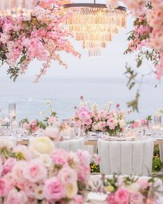 an outdoor dining area with pink flowers and chandelier