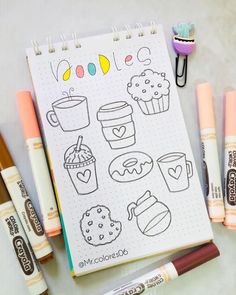 an open notebook with markers, pens and some food items on the page next to it