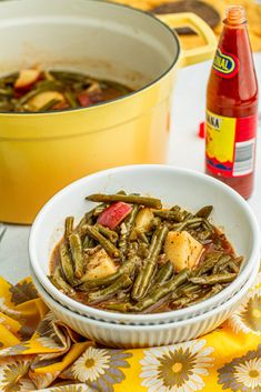 green beans and potatoes in a white bowl next to a yellow pot with mustard on the side