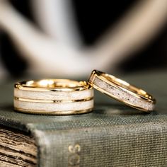 two wedding rings sitting on top of an old book