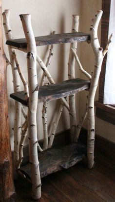 a shelf made out of branches in the corner of a room next to a window