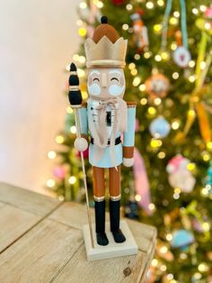 a nutcracker figurine on a table in front of a christmas tree