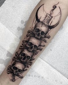 a black and white tattoo with three skulls on the arm, one skull is in the middle