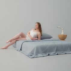 a woman sitting on top of a bed next to a pillow