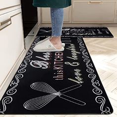 a woman standing on top of a kitchen floor next to a black mat with words and whisks