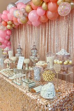 a table topped with lots of desserts and balloons in front of a gold sequin backdrop