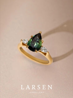 a gold ring with two pear shaped green and white diamonds