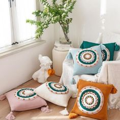 pillows on the floor in front of a window with a potted plant next to it