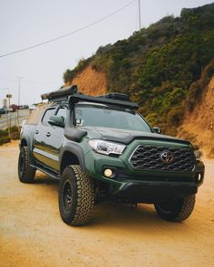 a green truck parked on top of a dirt road