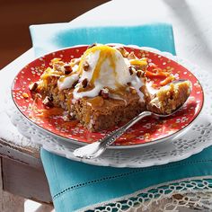 a red plate topped with a slice of cake covered in ice cream and toppings